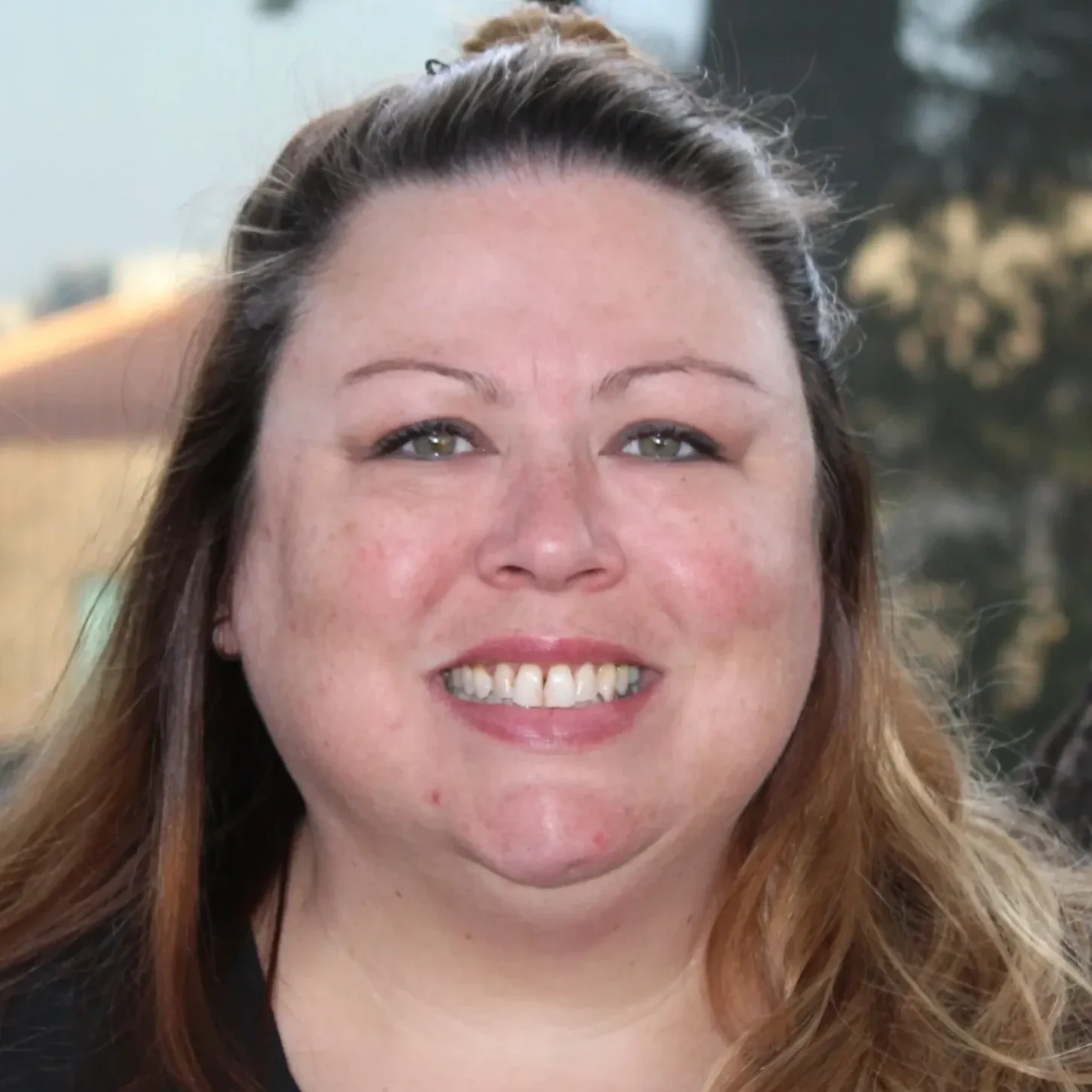 A woman with long hair and blue eyes smiling.