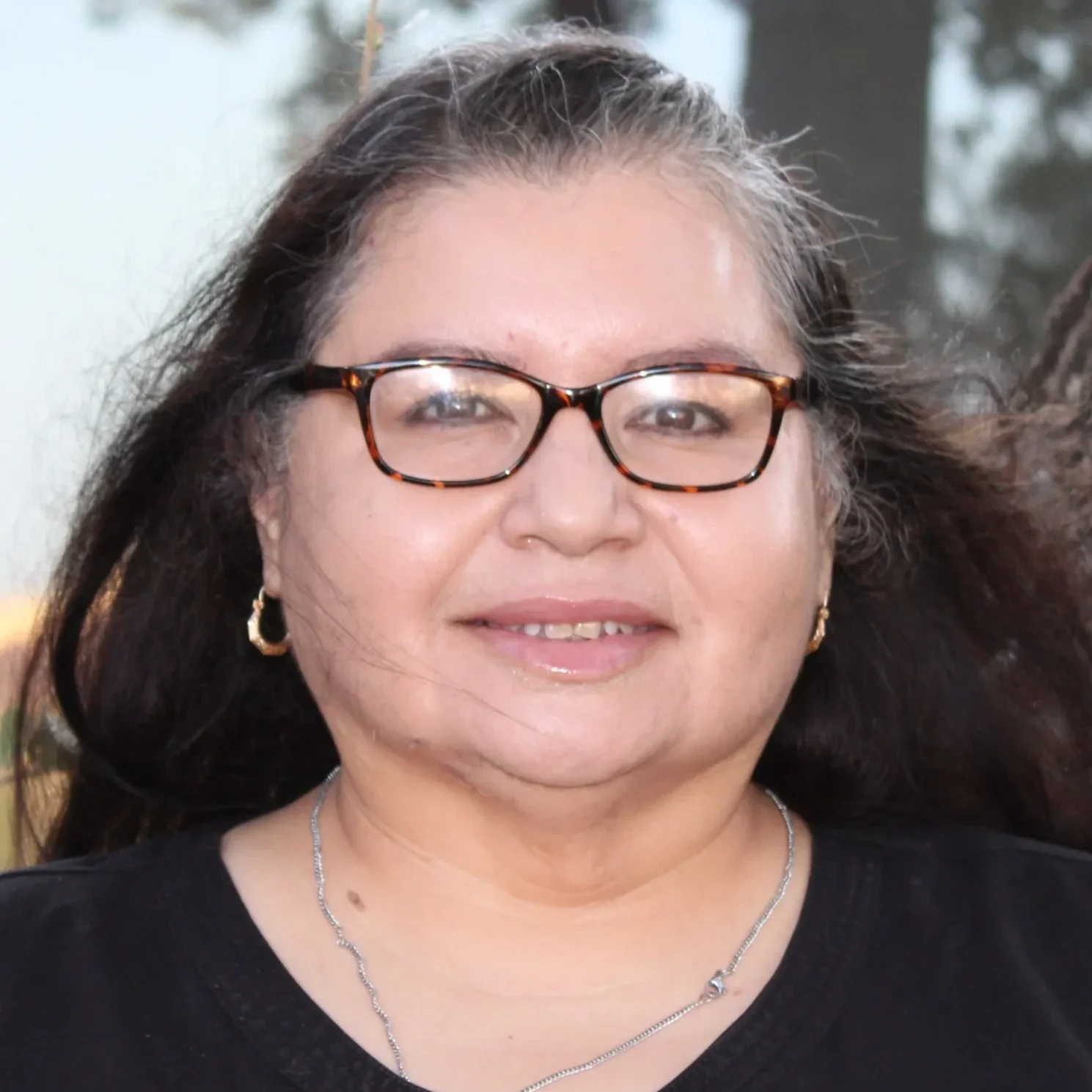 A woman with long hair wearing glasses and smiling.